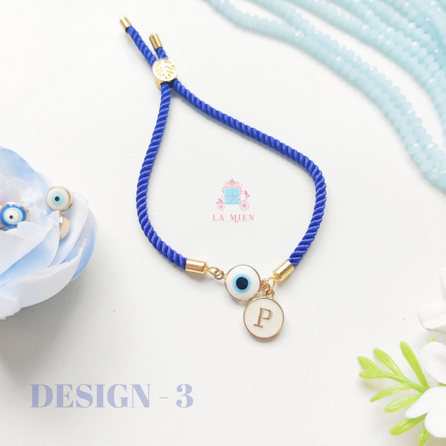 Minimal design evil eye rakhi bracelet with personalized initial and adjustable blue cord.