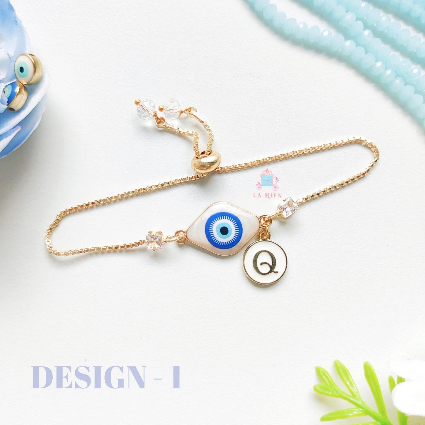 Classic evil eye rakhi bracelet with personalized initial charm and golden chain for Raksha Bandhan