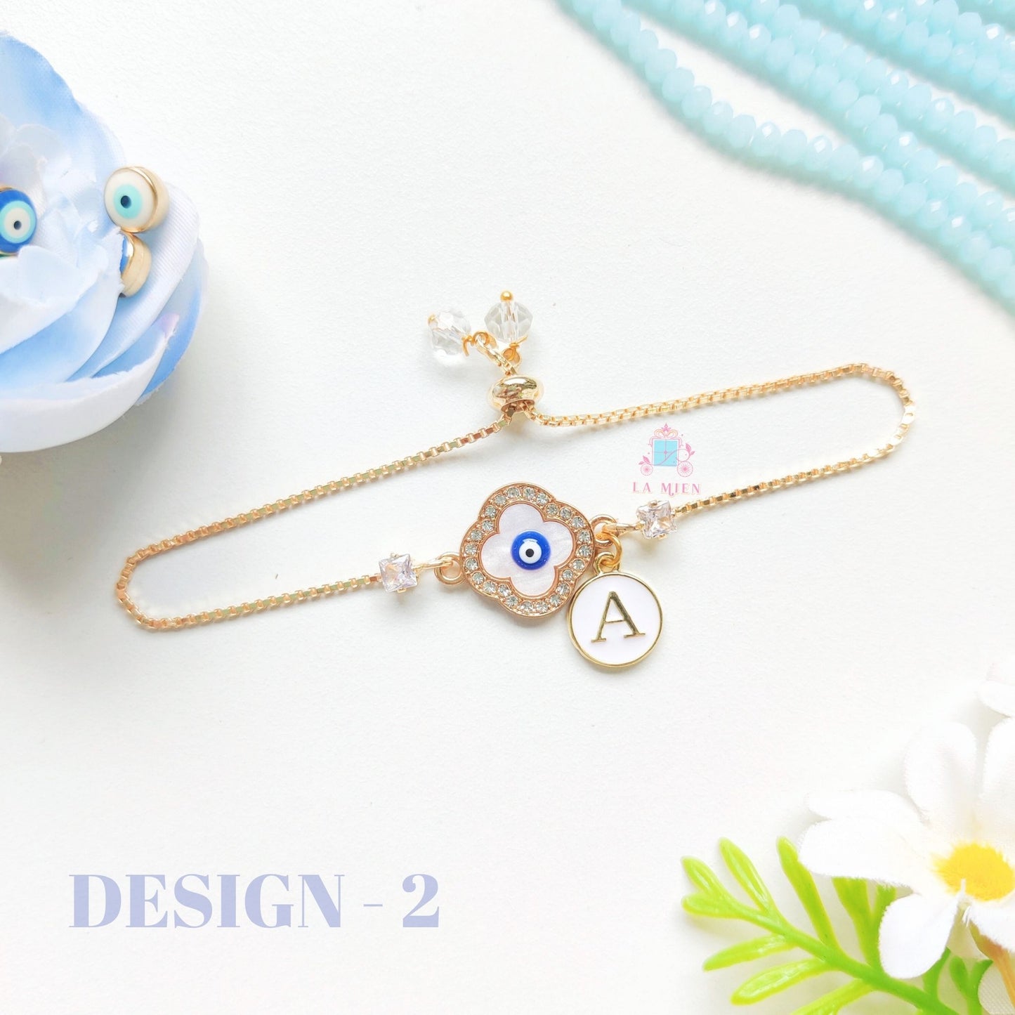 Evil eye rakhi bracelet with custom initial tag and elegant golden chain.