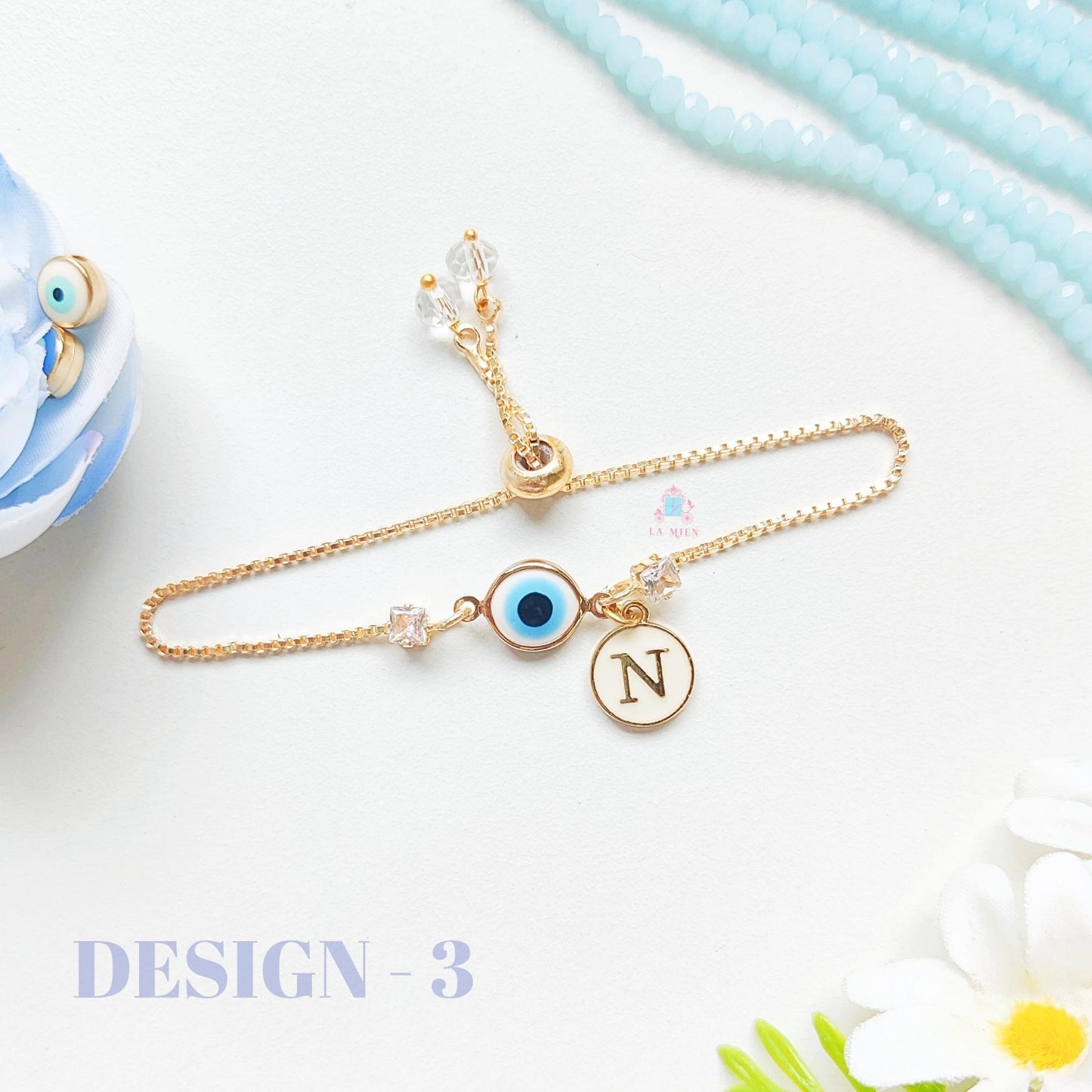 Minimal design evil eye rakhi bracelet with personalized initial charm on golden chain