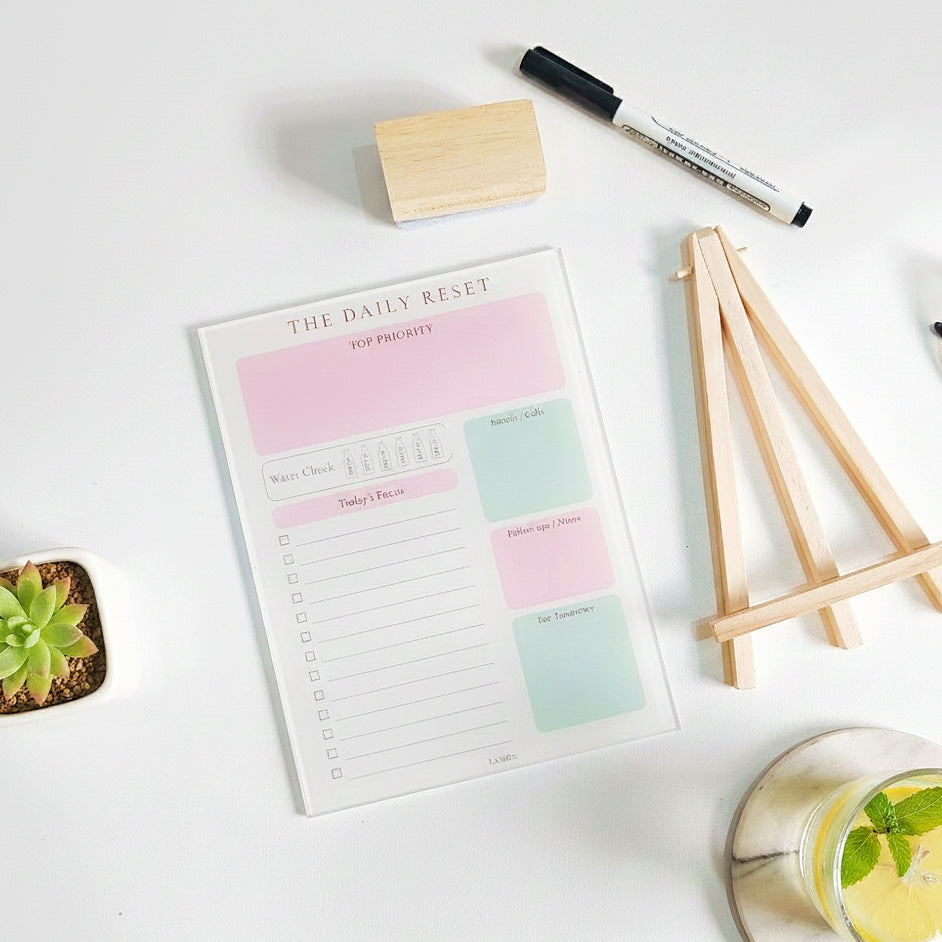 Daily reset reusable acrylic planner with sections for priorities, focus, notes, and hydration tracking in a calm productivity setup.